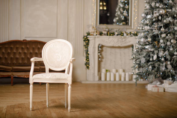istock Classic Christmas decorated interior room New year tree. Christmas tree with gold decorations. Modern white classical style interior design apartment with fireplace and armchair. 1154324826