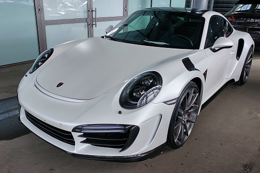 Moscow, Russia - April 29, 2019: Exclusive white matte Porsche 911 turbo in exclusive wide and carbon body kit named Stinger from Topcar tuning. Parked on the street. Front left side  view