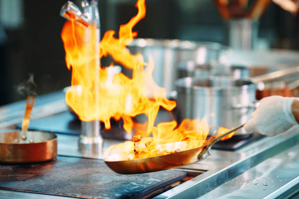 Professional chef cooking with fire and smoke in an outdoor kitchen, preparing fresh food at a country restaurant