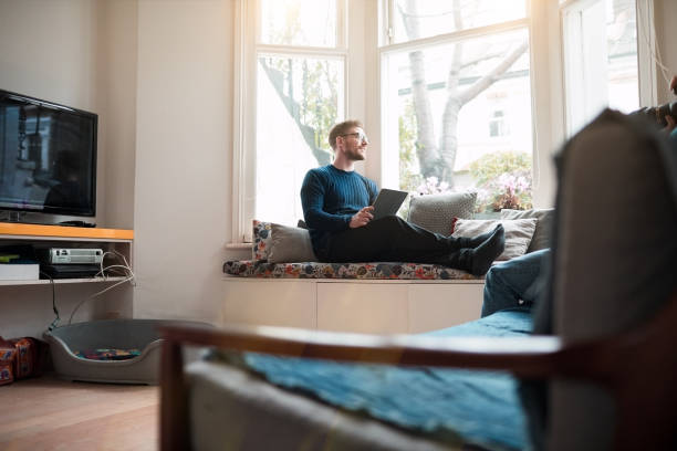 istock Young man relaxing at home, looking through window. 1154328791