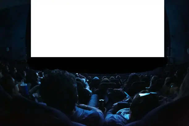 Photo of People in the cinema watching a movie. Blank empty white screen. Leisure entertainment concept.