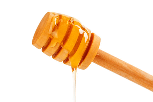 istock honey with wooden drizzler isolated on white background 1154329305