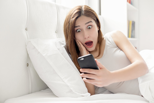 Young woman on smart phone with shocked