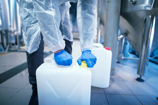 Industrial worker technologist working with chemicals in production plant.