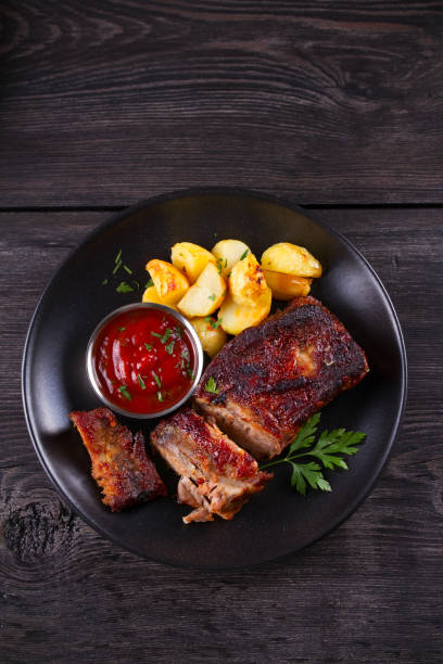 istock Roasted pork spare ribs with potatoes. Grilled meat 1154336743
