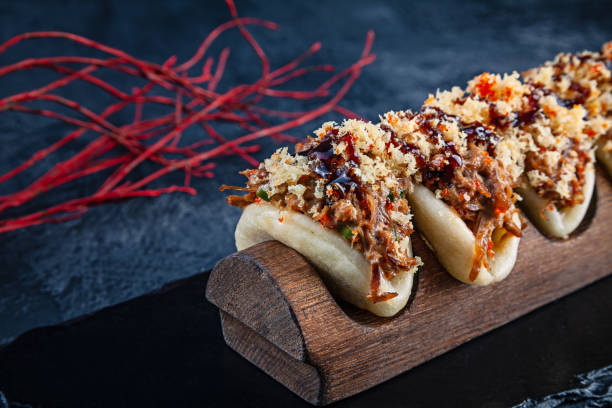 구 아 바오, 고기 찜 빵 (오리)을 닫습니다. 바오는 어두운 배경에 맛 있는 토핑으로 제공 됩니다. 아시아 요리. 아시아 샌드위치 찐 gua 바오. 일본 요리 패스트푸드 - japanese mustard 뉴스 사진 이미지