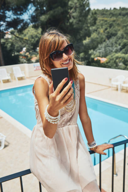 istock Cute young woman using cellphone near the swimming pool. 1154338514