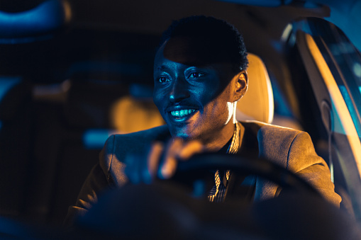 African-American businessman driving a car at night