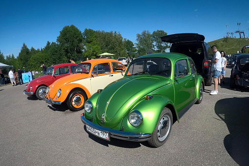 Moscow, Russia - June 01, 2019: Volkswagen beetle type 1 (Kaefer)  parked in row on the open parking on the street. Green, orange and red vw bugs. Meeting of the old retro classic cars