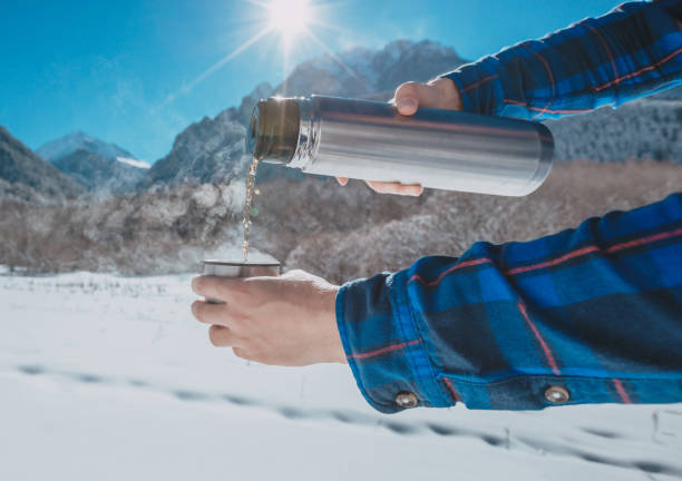 istock Man holding a thermos in on a snowy mountain 1154347993