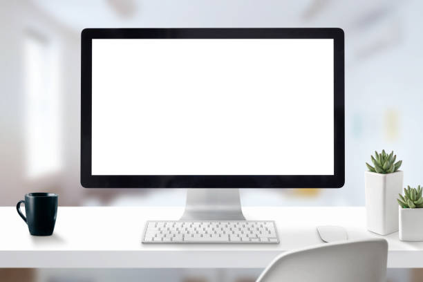 istock Computer display mockup. Office work desk with cup off coffee, keyboard, mouse, and plants. Office interior in background. 1154348352