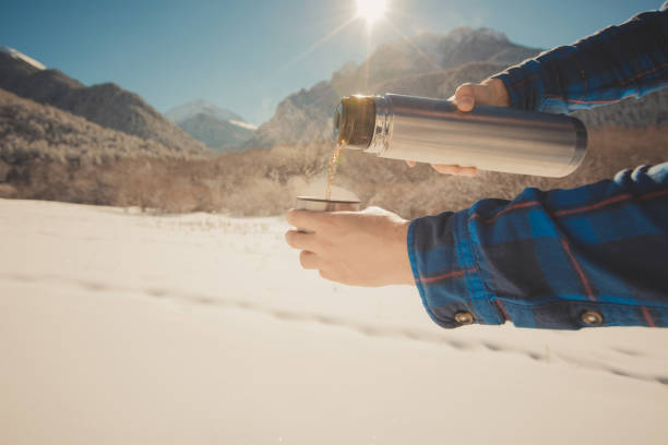 istock Man holding a thermos in on a snowy mountain 1154348465
