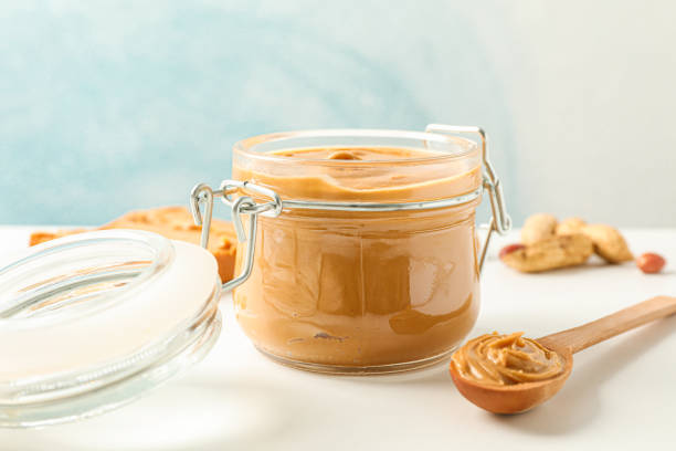 istock Composition with peanut butter sandwich, glass jar, peanut and spoon on white table against light background, space for text and closeup 1154352739