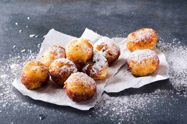 istock Closeupof deep fried cheese balls with powdered sugar on the baking paper, rustuc grey surface 1154354427