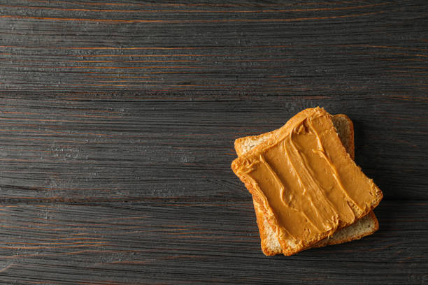istock Peanut butter sandwich on wooden background, space for text and top view 1154354822
