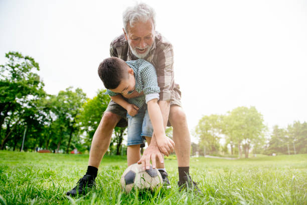 おじいちゃんと孫は楽しんで、サッカー - helmet child padding football helmet ストックフォトと画像