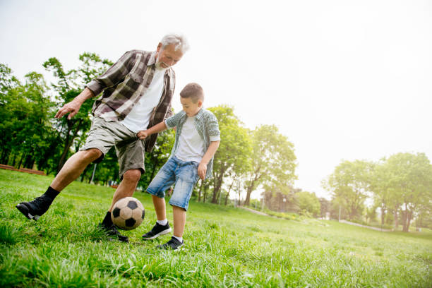 abuelo y nieto divirtiéndose, fútbol - helmet child padding football helmet fotografías e imágenes de stock