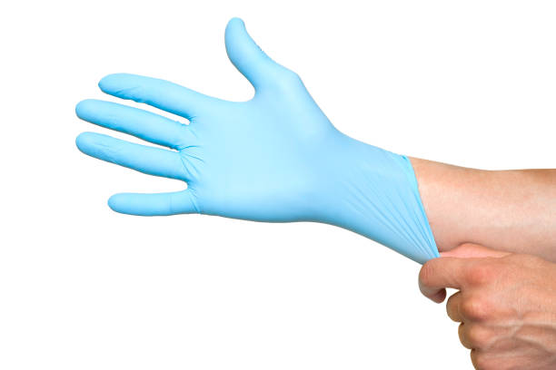 istock Doctor putting on protective blue gloves isolated on yellow background 1154361628