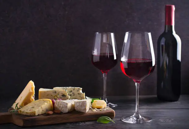 Photo of Red wine with cheese on chopping board. Wine and food concept