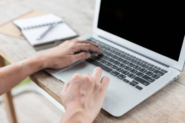 istock Woman hand using laptops and has a notebook and a pen with warm light on blurred background 1154368407