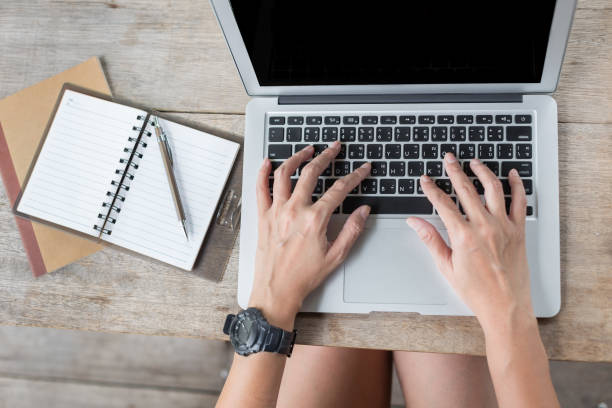 istock Woman hand using laptops and has a notebook and a pen with warm light on blurred background 1154368425