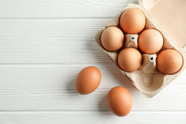 istock Brown chicken eggs in carton box on white background, space for text and top view 1154370663