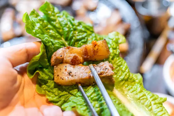 Photo of Pan-fried cooked black pork meal in Korea restaurant, fresh delicious korean food cuisine on iron plate with lettuce, close up, copy space, lifestyle