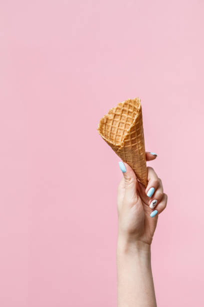 istock Woman holding waffle cones on color background. 1154377775