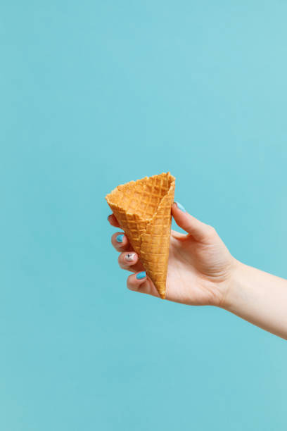 istock Woman holding waffle cones on color background. 1154377839