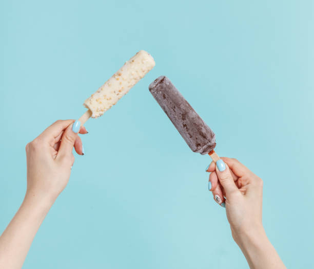 Woman holding ice cream on color background. Focus on hand.