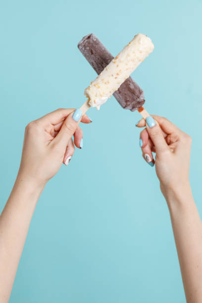 Woman holding ice cream on color background. Focus on hand.