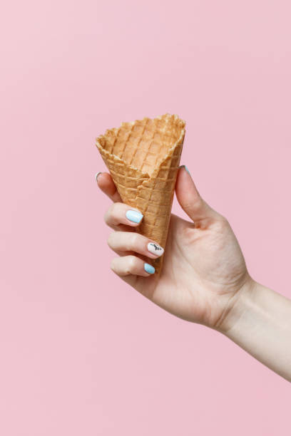 istock Woman holding waffle cones on color background. 1154378395