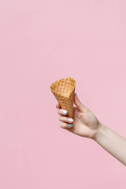 istock Woman holding waffle cones on color background. 1154378522