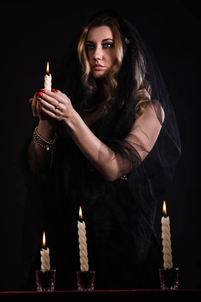 istock Young woman with a candle in darkness 1154378527