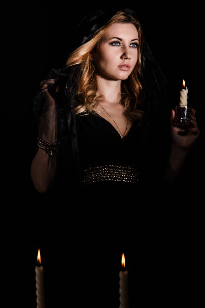istock Young woman with a candle in darkness 1154378545