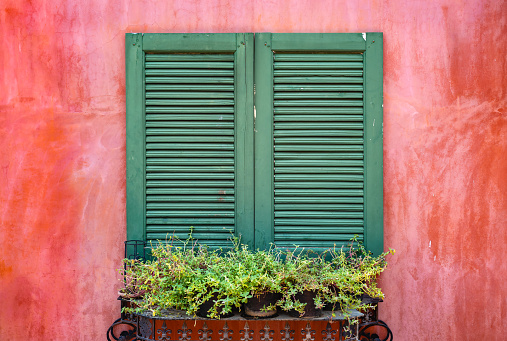Old green color wooden window at colorful red concrete wall.
