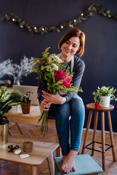 молодая творческая женщина в цветочном магазине. стартап флористского бизнеса. - sitting flower female studio shot стоковые фото и изображения