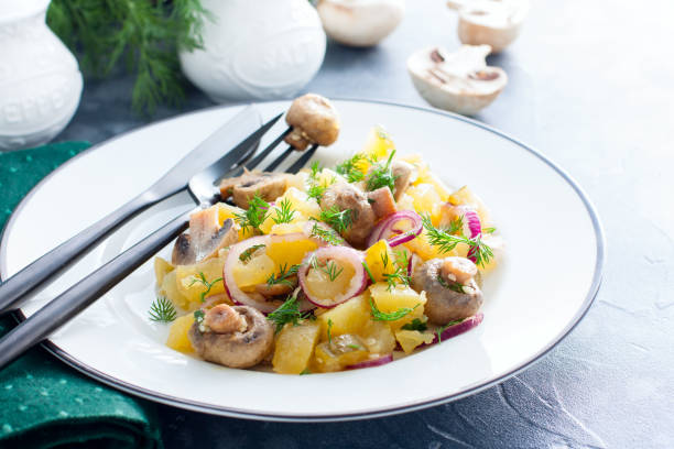 istock Potato salad with pickled champignons and cucumbers on a white plate, horizontal, copy space 1154384151