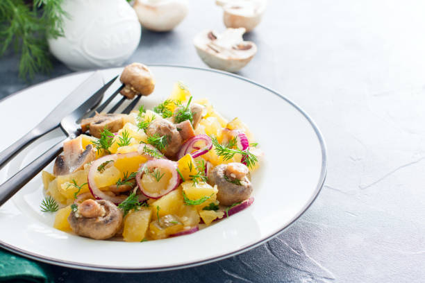 istock Potato salad with pickled champignons and cucumbers on a white plate, horizontal, copy space 1154384203