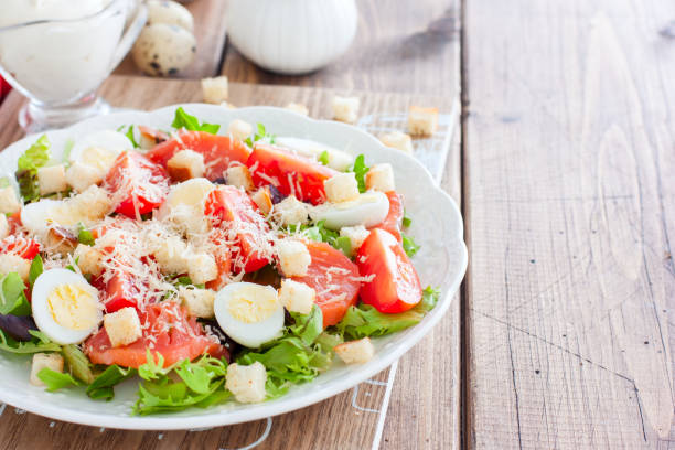 istock Caesar salad with salted salmon on a white plate, horizontal, copy space 1154384427