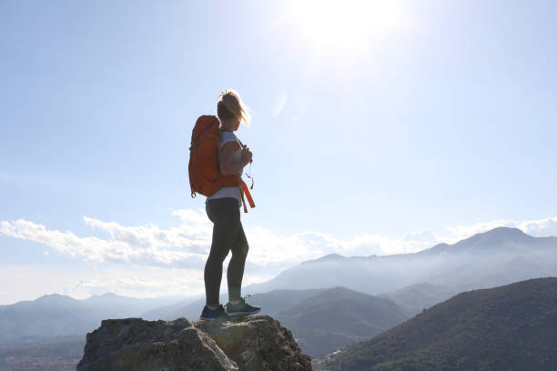 istock Young woman with backpack balances on rock in the mountains 1154386619