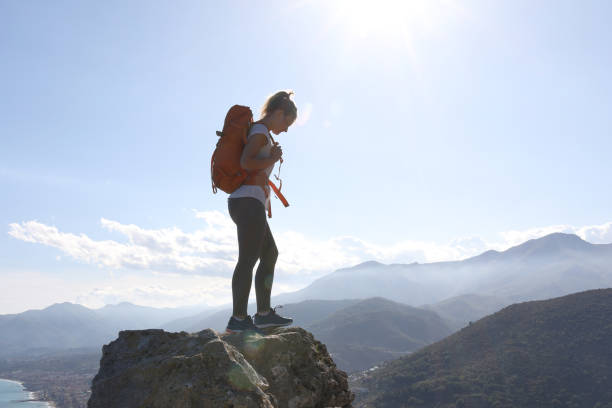 istock Young woman with backpack balances on rock in the mountains 1154386623
