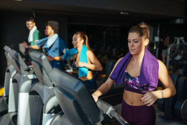 istock Young woman adjusting speed on a treadmill at gym 1154389054