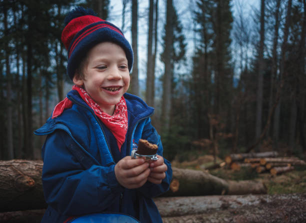 istock Little boy eating a candy bar on a mountain forest trip. 1154390243