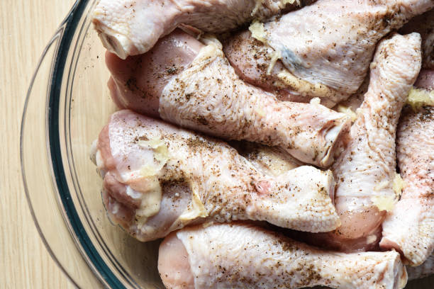 istock Raw chicken drumsticks are sprinkled with ground pepper, salt and garlic. 1154392072