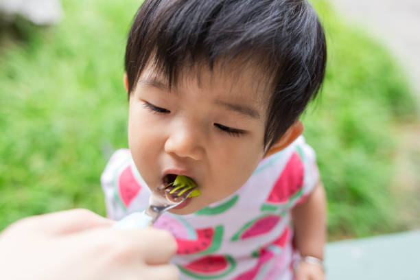 istock Mother feeding baby to eat fruit 1154395344
