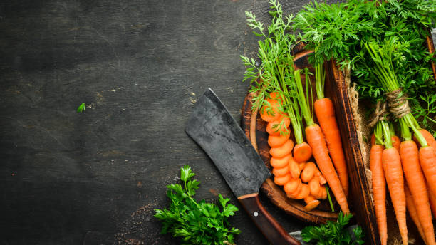 istock Fresh carrots on a black wooden background. Top view. 1154395426