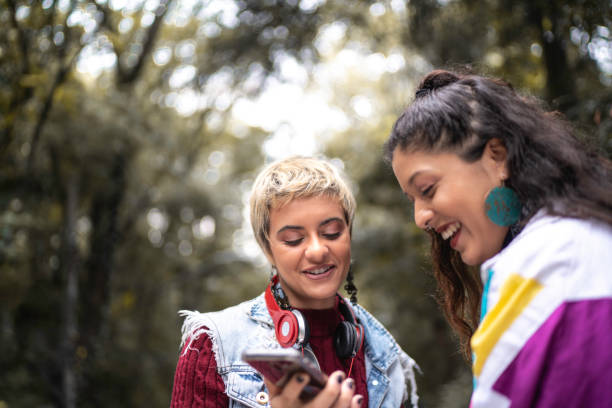 istock Latin friends using smartphone in the park 1154396797