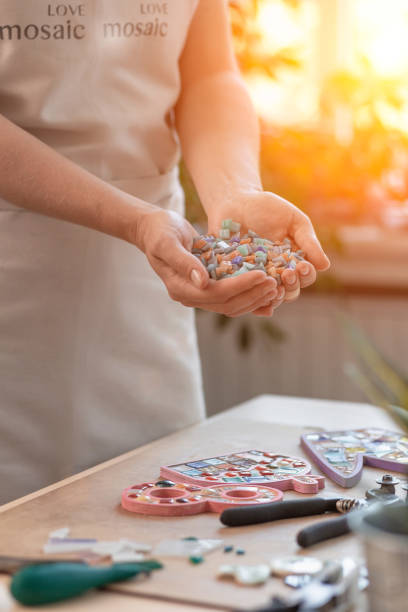 Workplace of the mosaic master: women's hands holding mosaic details in the process of making a mosaic
