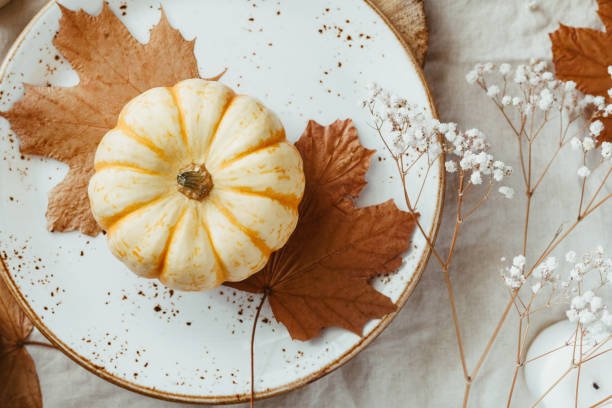 istock Top view on a decorated table setting for Thanksgiving dinner. Autumn ornate, white pumpkin on ceramic plates. 1154396843